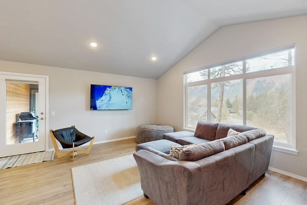 Modern radiant floor heating is the subtle operational detail that turns a winter ski trip into a true luxury upgrade—and Girdwood Vibes Unit B features it throughout the entire open-concept floor plan. Located within easy walking distance of Alyeska Resort and the Virgin Creek Trailhead, this suite handles family logistics effortlessly. The interior features an oversized living room sofa, a large custom bean bag, a massive Smart TV, and a full kitchen with stainless steel appliances. The dedicated kid's room comes fully stocked with toys, books, and games to handle the entertainment heavy lifting, while the back deck opens out to a shared grilling area framed by clean mountain peaks. Standard Specs: Full kitchen with stainless steel appliances, radiant floor heating, shared deck with gas grill, private washer/dryer, flat-screen Smart TV, child's toys, games, books, Pack-N-Play, high-speed WiFi, and keypad entry. Parking for two vehicles. No A/C. Sleeps 6.