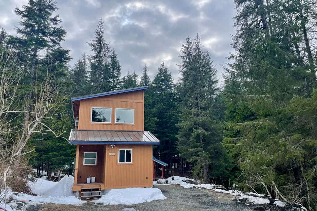 The exact kind of bright, open-concept one-bedroom home you would actually choose to live in full-time. Large upper-level architectural windows pull the mountain and valley views right into the main living room, while a private balcony pushes you straight out into the fresh Girdwood air. The intelligent multi-level layout features a full eat-in dining bar, an updated kitchen, and a lower-level master bedroom with an oversized walk-in closet and private laundry. A dedicated downstairs bonus room cleanly handles yoga practice, remote work, or quiet gear storage. Located a brief drive to Alyeska Resort and steps from local trail loops and breweries. Standard Specs: Full kitchen with dishwasher, private balcony, walk-in closet, full-size utility washer/dryer, dedicated yoga/storage room, board games, flat-screen TV with Netflix streaming, high-speed WiFi, and keypad entry. Driveway parking for two vehicles. Sleeps 5.