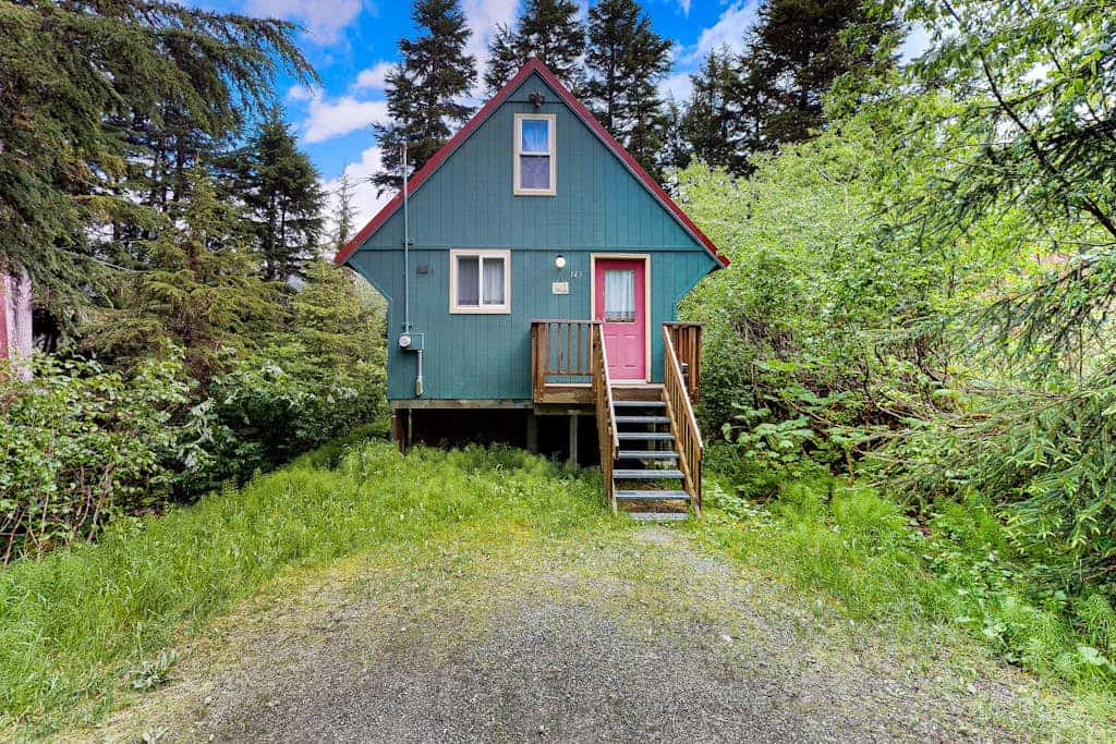 Christina Cabin is small on purpose. Tucked quietly into the forest under two miles from Alyeska Resort, this quaint alpine A-frame is an intentional, artsy retreat where the noise of the rest of the world completely disappears. The hand-styled interior features custom personal touches and high-quality furnishings, while the back patio holds a brand-new private hot tub enclosed by a custom wood privacy fence. Walk straight out your door to access local hiking loops, or take a quick drive to the village dining spots and aerial tramway. A clean, romantic space built for purists. Standard Specs: Well-equipped kitchen, private outdoor hot tub with privacy fencing, flat-screen TV, high-speed WiFi, and keypad entry. Driveway parking for two vehicles. Strict compliance with local quiet hours (10 PM–8 AM) and non-smoking premises. Sleeps 2.