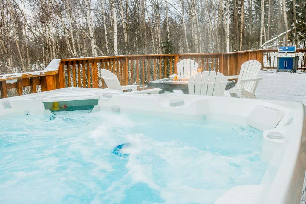 Twenty minutes north of downtown Anchorage, the city quiets and the birch forest takes over. Queens Birch Lodge is a cabin-styled retreat tucked deeply into that canopy—featuring towering windows that bring the old-growth woods into nearly every room. The outdoor living area is built for long northern evenings, offering a porch swing out front, an upscale hot tub on the back deck, a private gas grill, and a premium fire table. Inside, discovery awaits with a gas fireplace, a full kitchen with a granite prep island, an upright piano, and a dedicated executive home office space. Standard Specs: Full kitchen with granite island, private hot tub, fire table, gas fireplace, upright piano, standalone office desk, private laundry, high-speed WiFi, and keypad entry. Driveway parking for up to three vehicles. Enforces strict maximum occupancy rules. Sleeps 6.