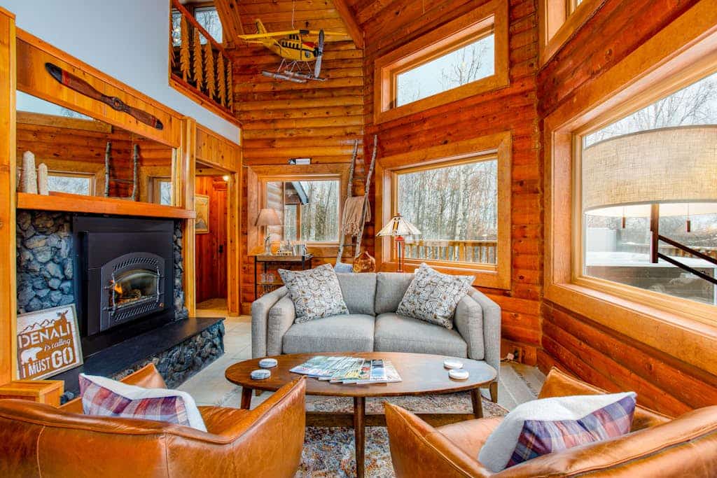 Twenty minutes north of downtown Anchorage, the city quiets and the birch forest takes over. Queens Birch Lodge is a cabin-styled retreat tucked deeply into that canopy—featuring towering windows that bring the old-growth woods into nearly every room. The outdoor living area is built for long northern evenings, offering a porch swing out front, an upscale hot tub on the back deck, a private gas grill, and a premium fire table. Inside, discovery awaits with a gas fireplace, a full kitchen with a granite prep island, an upright piano, and a dedicated executive home office space. Standard Specs: Full kitchen with granite island, private hot tub, fire table, gas fireplace, upright piano, standalone office desk, private laundry, high-speed WiFi, and keypad entry. Driveway parking for up to three vehicles. Enforces strict maximum occupancy rules. Sleeps 6.
