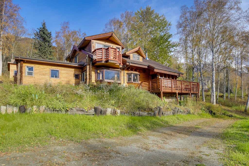 The cabin sits exactly where the road runs out—thirty minutes outside of Anchorage and fifteen minutes from downtown Eagle River, completely embedded inside a rugged wilderness where moose move through the yard and the northern lights handle the winter sky. Constructed with traditional log walls and framing picture windows, the home features a classic wood stove, a master bedroom loft with an en-suite bath, and a large viewing deck. Engineered for remote professionals, the cabin includes dedicated high-speed WiFi and a workspace docking station packed with two desktop monitors. Located two miles from the Eagle River Nature Center trail loops and salmon-viewing deck. *Winter notice: 4WD strictly required.* Standard Specs: Fully equipped kitchen with dishwasher, wood stove, executive desk workspace with dual monitors, viewing deck, private laundry, high-speed WiFi, and safety tools. Driveway parking for three vehicles (steep loop). Dog-friendly. No parties/strict quiet hours. Sleeps 6.