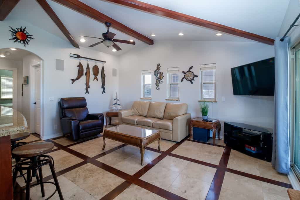 Welcome to Copper Bottom Cottage, a four-bedroom waterfront retreat in the channels of gated Long Island Village. Gather on the spacious covered deck above the canal, fish from the water's edge, and spread out across two levels with room for eight. The lower unit has its own entrance, and every bedroom has a streaming TV. Your stay includes the community's indoor and outdoor pools, hot tubs, par-3 golf, tennis, and marina, with South Padre Island beaches about ten minutes over the causeway.