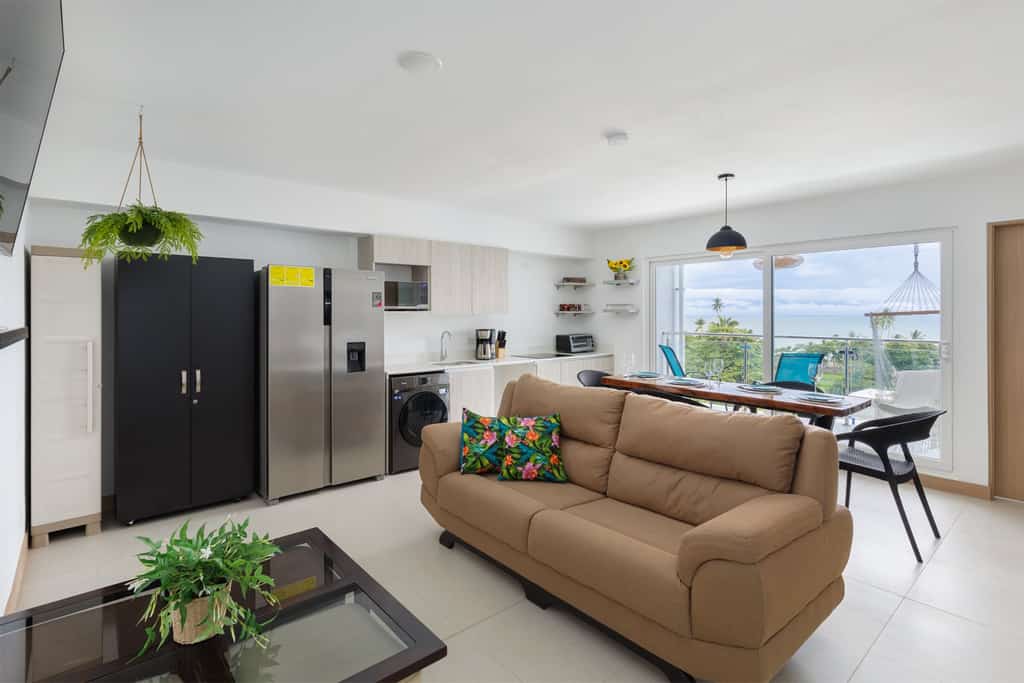 Welcome to our serene and stylish condo, where nature meets comfort. This two-bedroom, one-bathroom retreat is adorned with vibrant toucan motifs and lush greenery, creating a unique atmosphere. The cozy living area features colorful artwork and plants, while the fully equipped kitchen offers modern appliances and ample space for home-cooked meals. Each bedroom provides plush bedding, storage, and natural light. The bathroom is modern with a spacious shower and essential toiletries. The expansive terrace is a highlight, perfect for soaking up the sun or enjoying a morning coffee. It’s furnished with comfortable seating, including a hanging chair, offering breathtaking sea views. Additional amenities include high-speed Wi-Fi, air conditioning, and a flat-screen TV. The condo complex also boasts a stunning pool area for refreshing dips and relaxation. Experience the perfect blend of nature and comfort at our toucan-themed condo. Book your stay today and enjoy an unforgettable coastal retreat