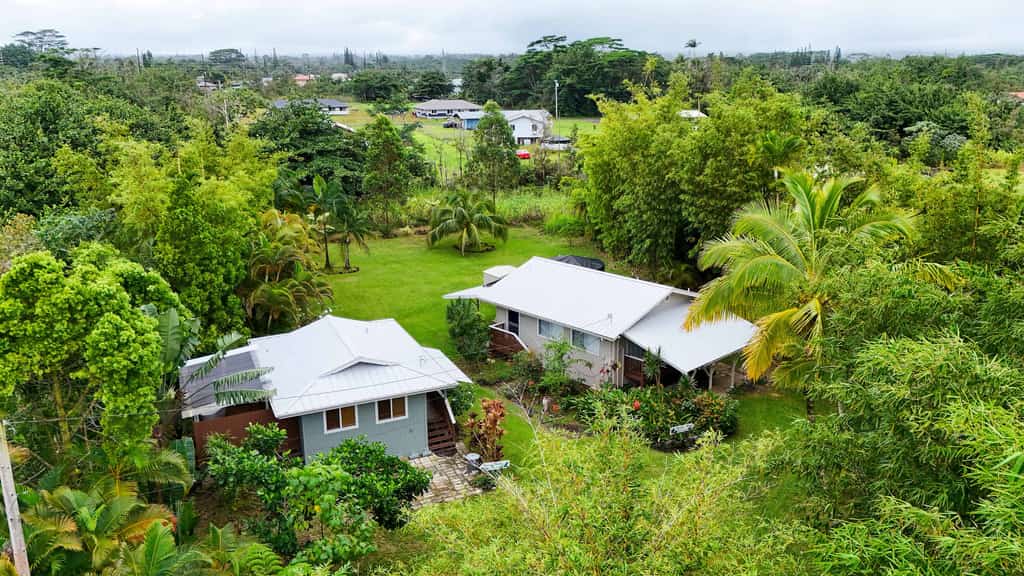 Experience the perfect Hawaiian getaway at this unique property in Keaau featuring two comfortable homes on a single spacious lot. Ideal for families or groups, this peaceful retreat offers a serene garden view, fully equipped kitchens, and relaxing outdoor lanais. Enjoy the convenience of modern amenities including free parking and a full kitchen while being just a short drive from stunning beaches and breathtaking waterfalls. Your tranquil island escape awaits in this beautiful rural setting.