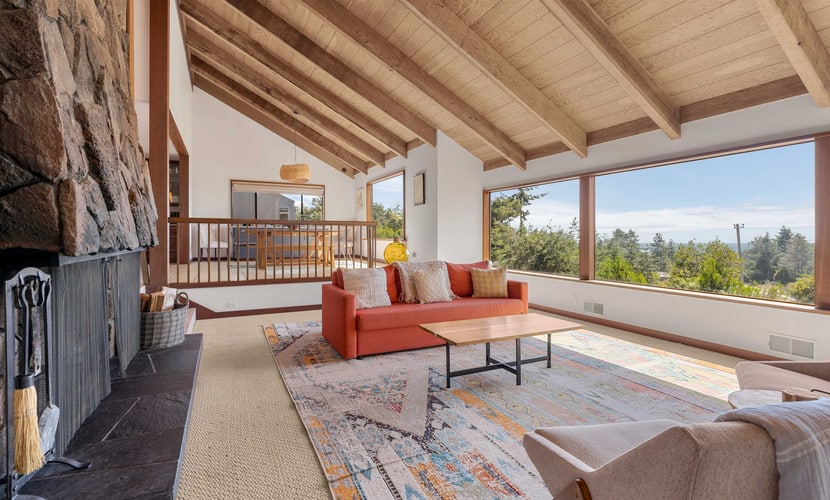Expansive ocean views from the living room, dining table, and primary bedroom, and a chef's kitchen guests call top notch, with a gas range, air fryer, stocked spice rack, and a monster dining table for meals and puzzles. Floor-to-ceiling stone wood-burning fireplace, private hot tub on the enclosed courtyard, fenced yard for kids and the dog, EV charger. Sleeps 8 in 3 queens plus a sleeper sofa. Trail below the house; Shell Beach is a 15-to-20-minute walk. One pup per stay.