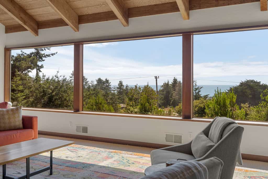 Expansive ocean views from the living room, dining table, and primary bedroom, and a chef's kitchen guests call top notch, with a gas range, air fryer, stocked spice rack, and a monster dining table for meals and puzzles. Floor-to-ceiling stone wood-burning fireplace, private hot tub on the enclosed courtyard, fenced yard for kids and the dog, EV charger. Sleeps 8 in 3 queens plus a sleeper sofa. Trail below the house; Shell Beach is a 15-to-20-minute walk. One pup per stay.