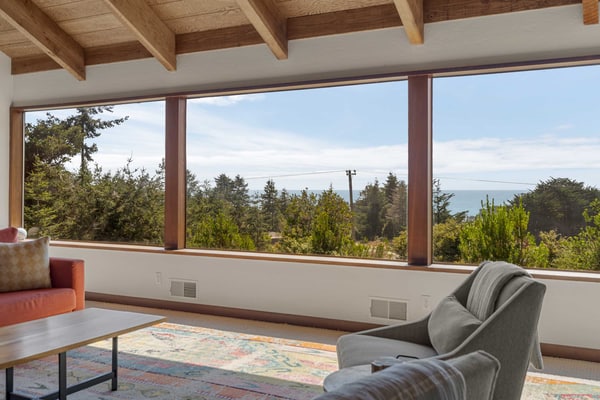 Expansive ocean views from the living room, dining table, and primary bedroom, and a chef's kitchen guests call top notch, with a gas range, air fryer, stocked spice rack, and a monster dining table for meals and puzzles. Floor-to-ceiling stone wood-burning fireplace, private hot tub on the enclosed courtyard, fenced yard for kids and the dog, EV charger. Sleeps 8 in 3 queens plus a sleeper sofa. Trail below the house; Shell Beach is a 15-to-20-minute walk. One pup per stay.