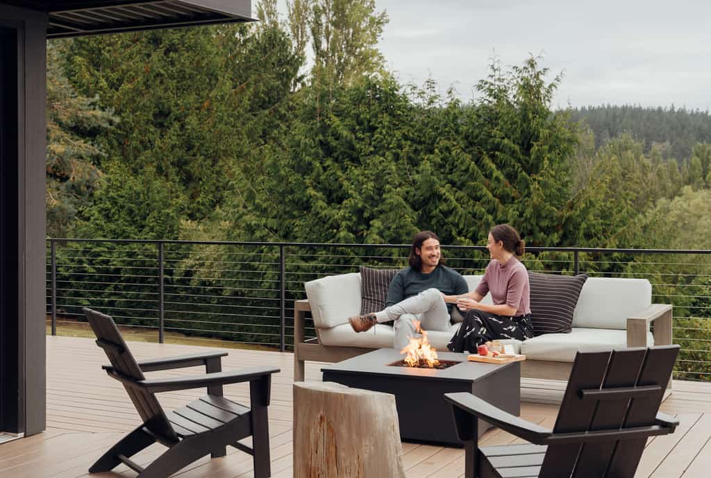 Couple sitting on a couch from an outdoor patio with a fire pit.