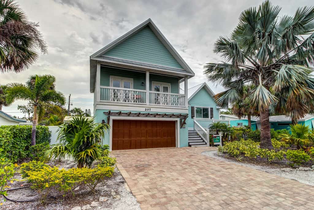 Blue vacation rental with a cobblestone style driveway in Anna Maria, FL.