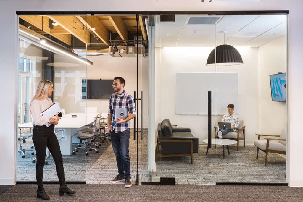 Employees chatting outside a conference room at the Vacasa office
