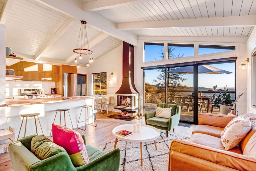 bright living room featuring a fireplace, cozy furnishings, and mountain views glass doors leading to the deck