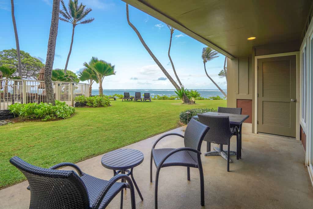 covered resort patio facing lush manicured grounds and ocean in hawaii
