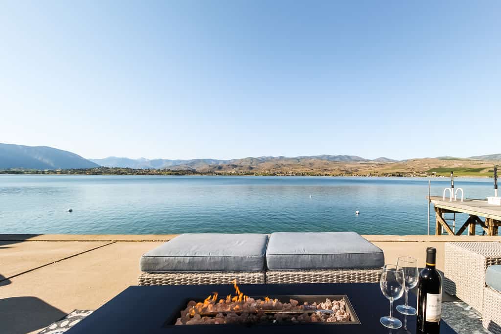 Fire pit with wine, dock, and chairs overloking Lake Chelan.