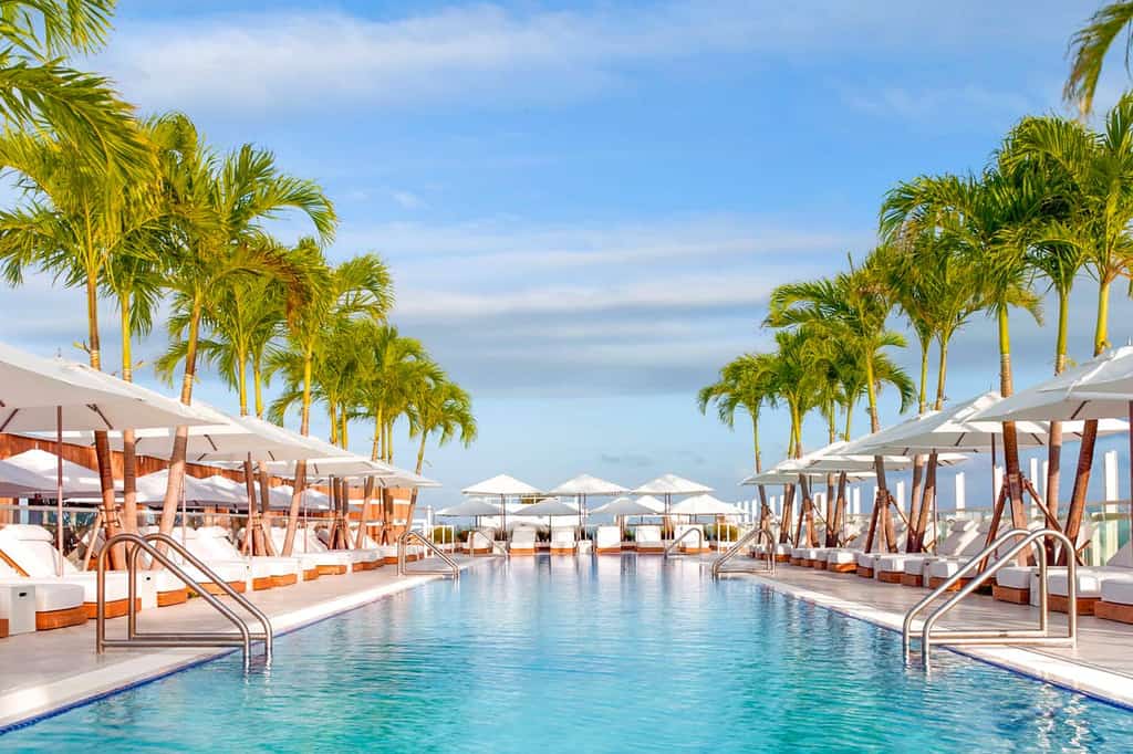 Resort style pool with luxurious pool chairs and white sun umbrellas in Miami, FL.