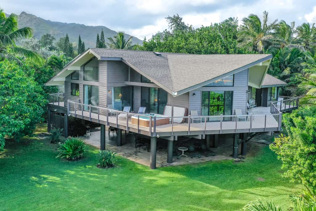 luxurious hawaii vacation home with outdoor hot tub and wraparound deck surrounded by lush greenery