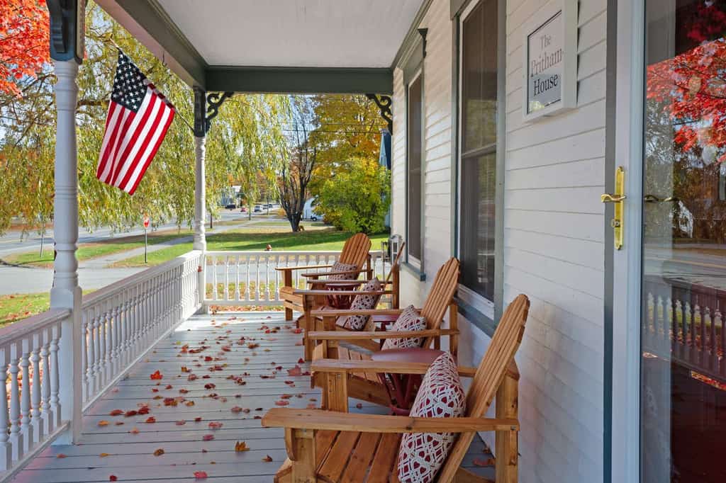 moosehead lake vacation home with covered front porch with adirondack chairs and an american flag