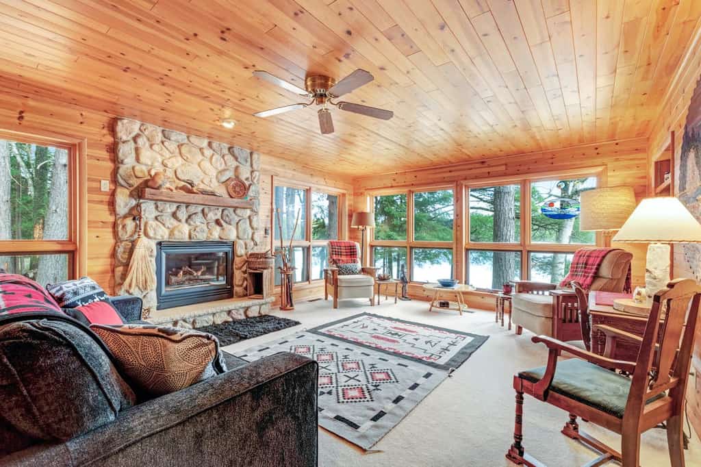 Interior of Eagle River, WI cabin with ample seating, a stone fireplace, and adorable accents