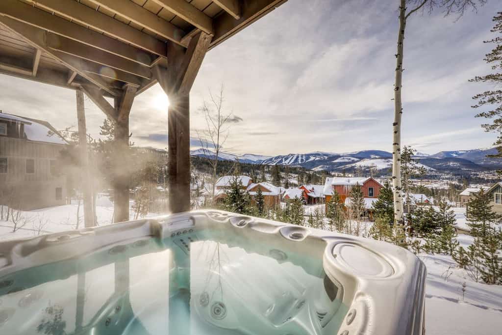 The hot tub overlooking Fraser, CO at a cabin rental as seen in the winter.