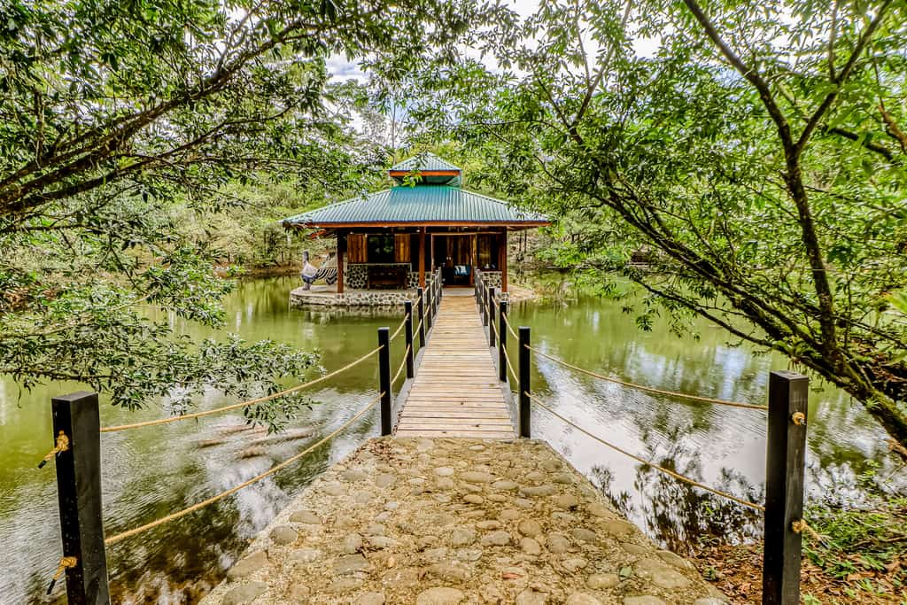 The entrance of a Alajuela vacation rental surrounded by water leading to a bridge.