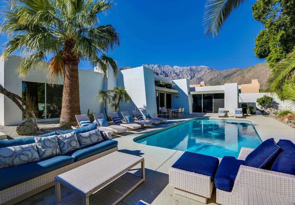 Contemporary style vacation home rental with an outdoor pool and comfortable lounge chairs in Palm Springs, CA.