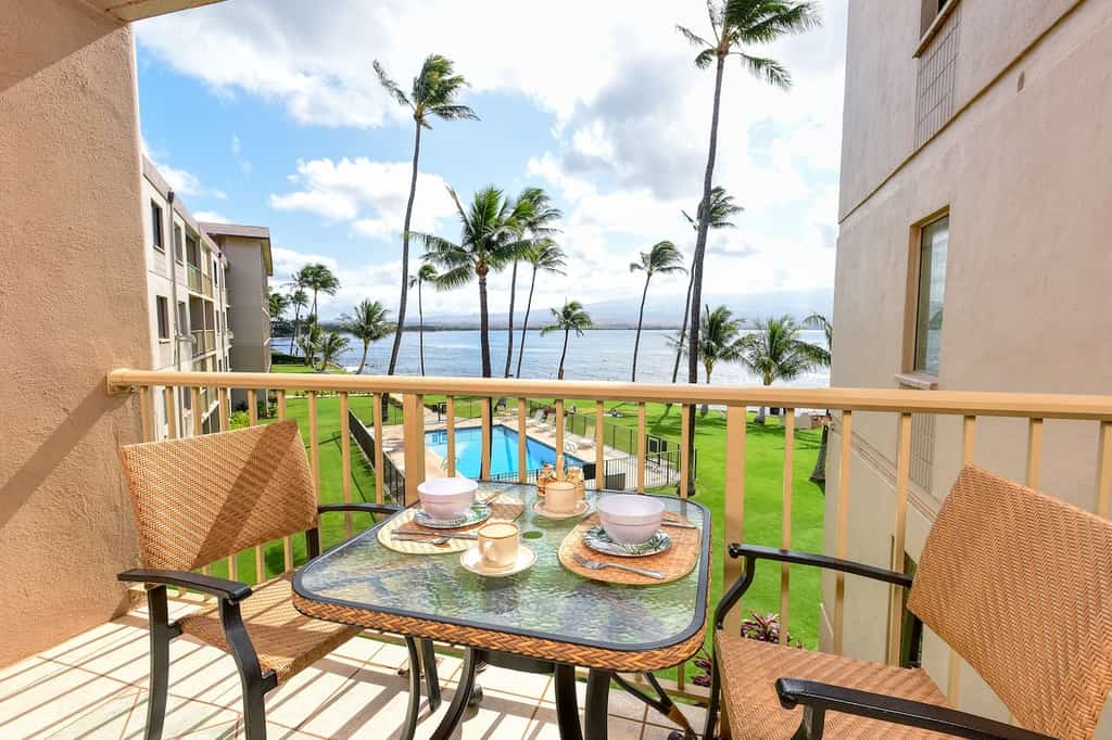 A balcony with table and chairs at a vacation rental in Maalaea Kai.