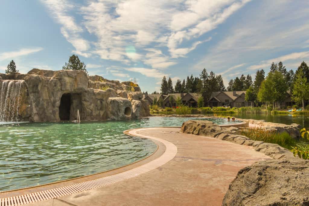 Resort outdoor pool with a waterfall and cave near a river in Sun River, OR.