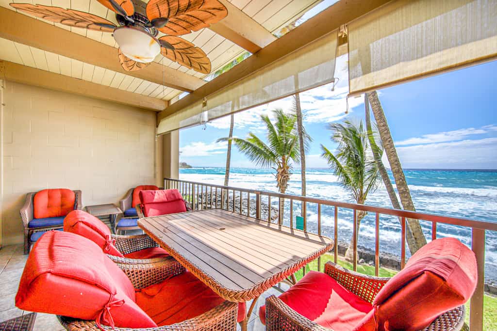 covered resort patio with views of ocean waves, beach, and palm trees