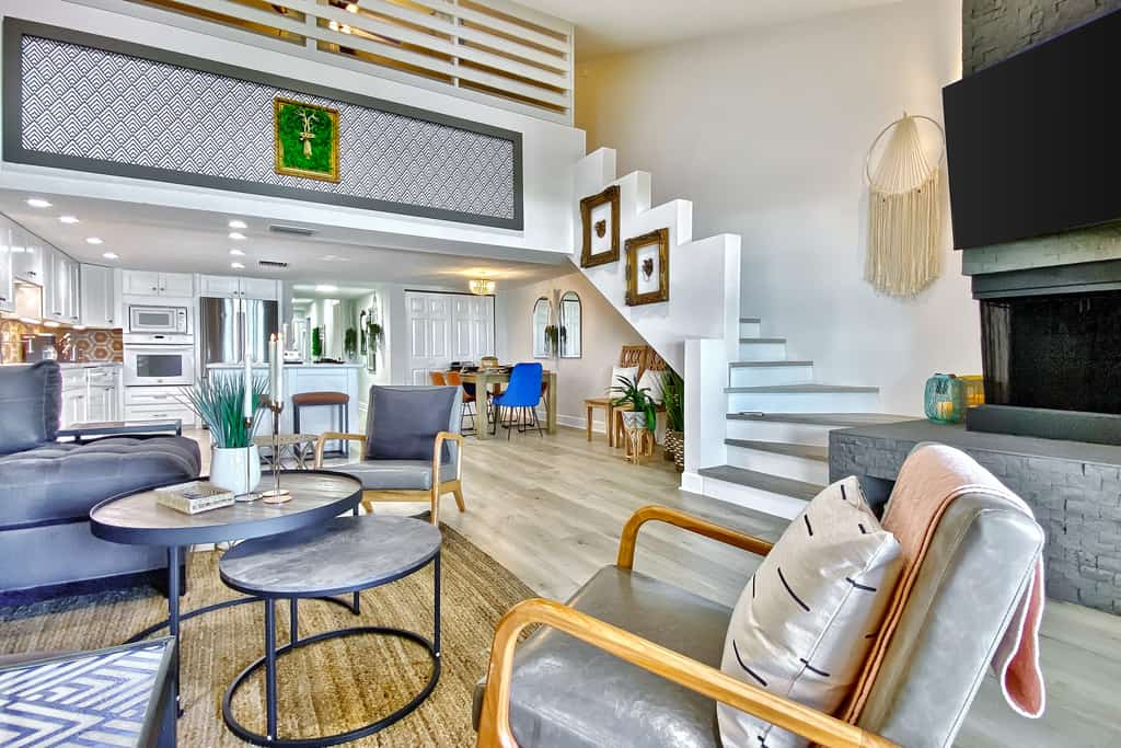 chic living space with chair, circular coffee tables, a fireplace, and a tv with white stairs leading upstairs