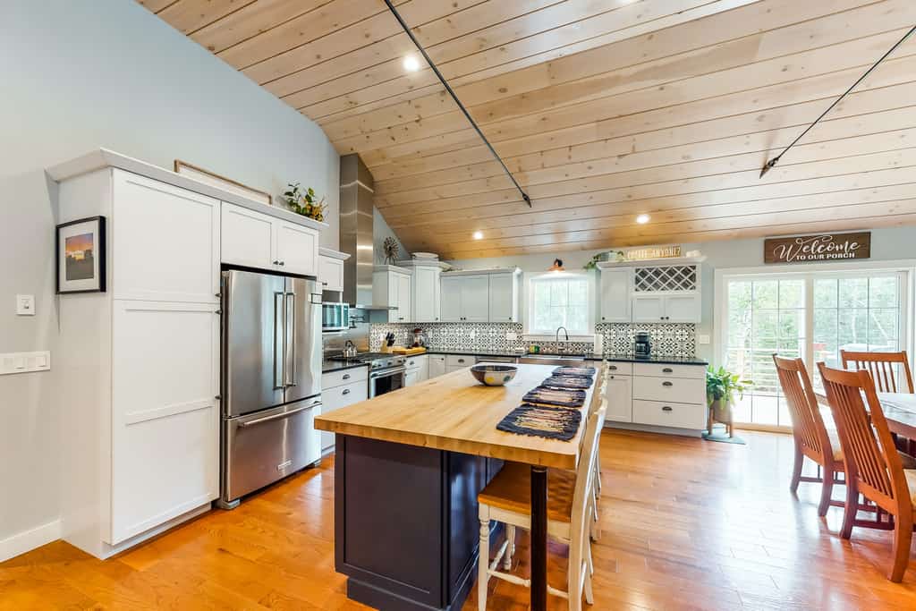 airy, open kitchen with tiled backsplash, stainless steel appliances, and a spacious island
