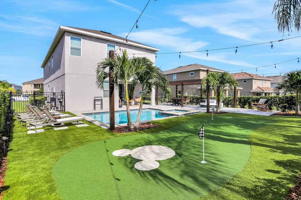 The backyard of a vacation rental with a putting green with a Micky face on it.