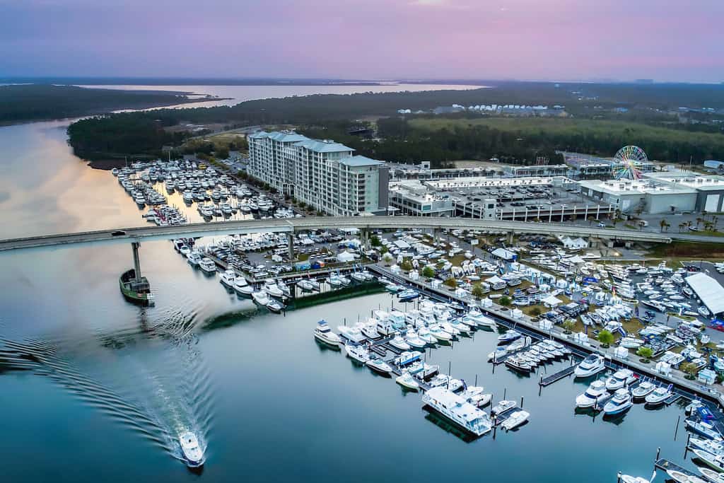 Aerial shot of the Blue Water Condos highlighting the building, a bridge, a marina, and other activities surrounding the structure.