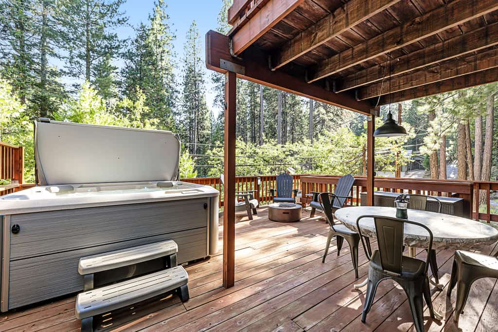 The outdoor area with a hot tub and firepit at a a-frame cabin rental in Arnold, California.