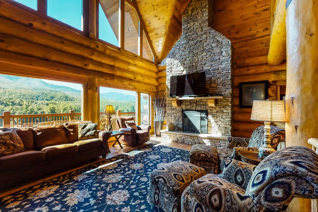 Large stone indoor fire place in a log cabin with large windows and mountain views in Gatlinburg, TN