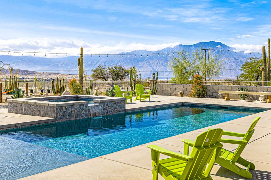 The pool area with a mountain view and a hot tub at a vacation rental in Desert Hot Springs, CA.