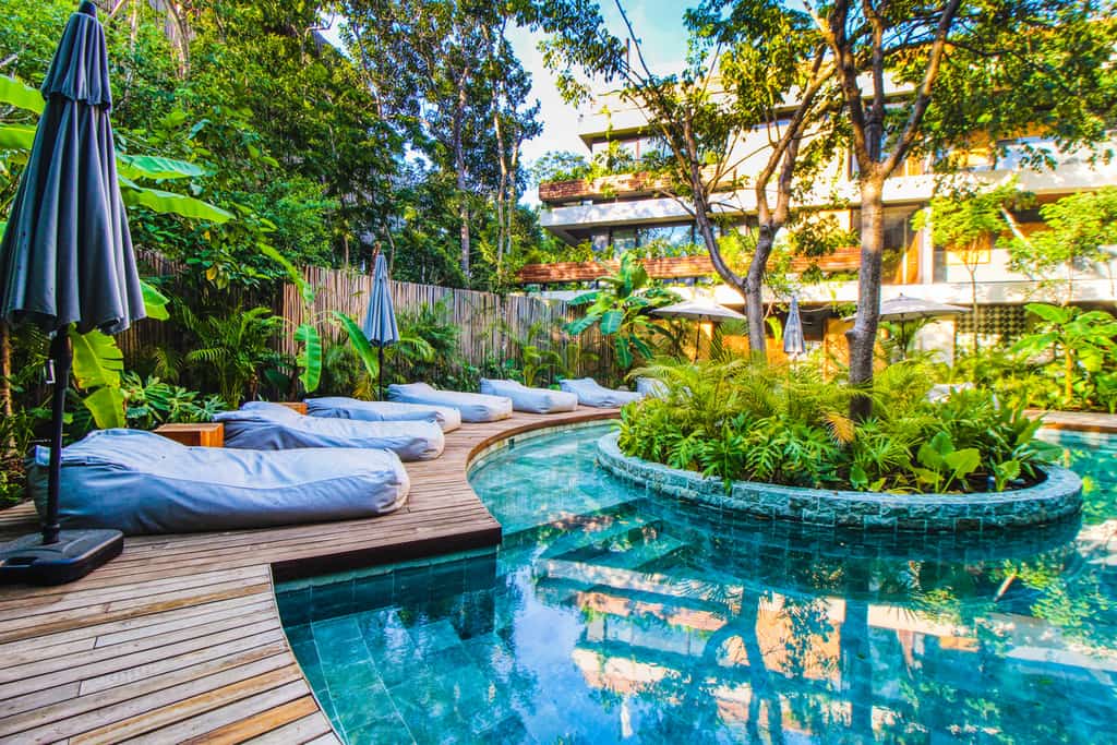 tropical style outdoor pool with beds lined along the deck