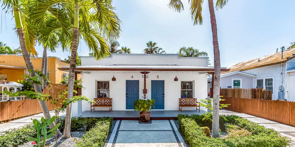 Adorable Key West bungalow with blue doors and outdoor benches.