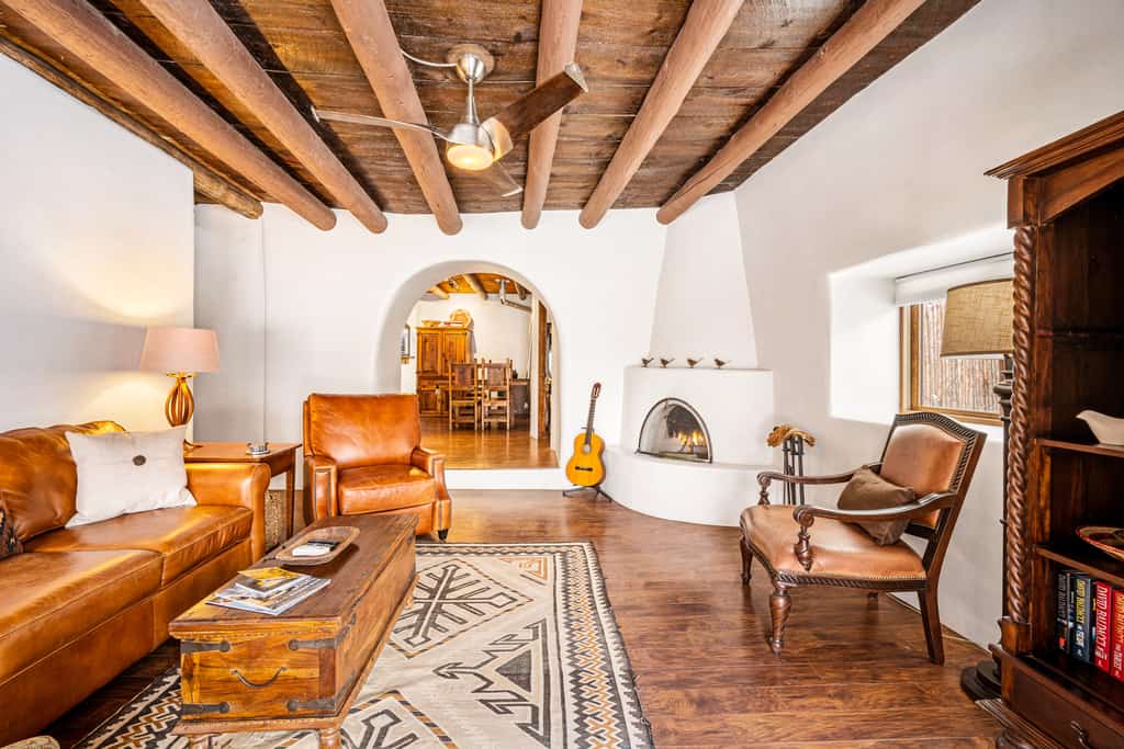 living room of pueblo-style vacation home with adobe fireplace, guitar, exposed beams, and southwestern style.