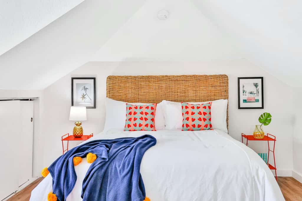 Bright vacation home bedroom with white walls, white bed and red night stands