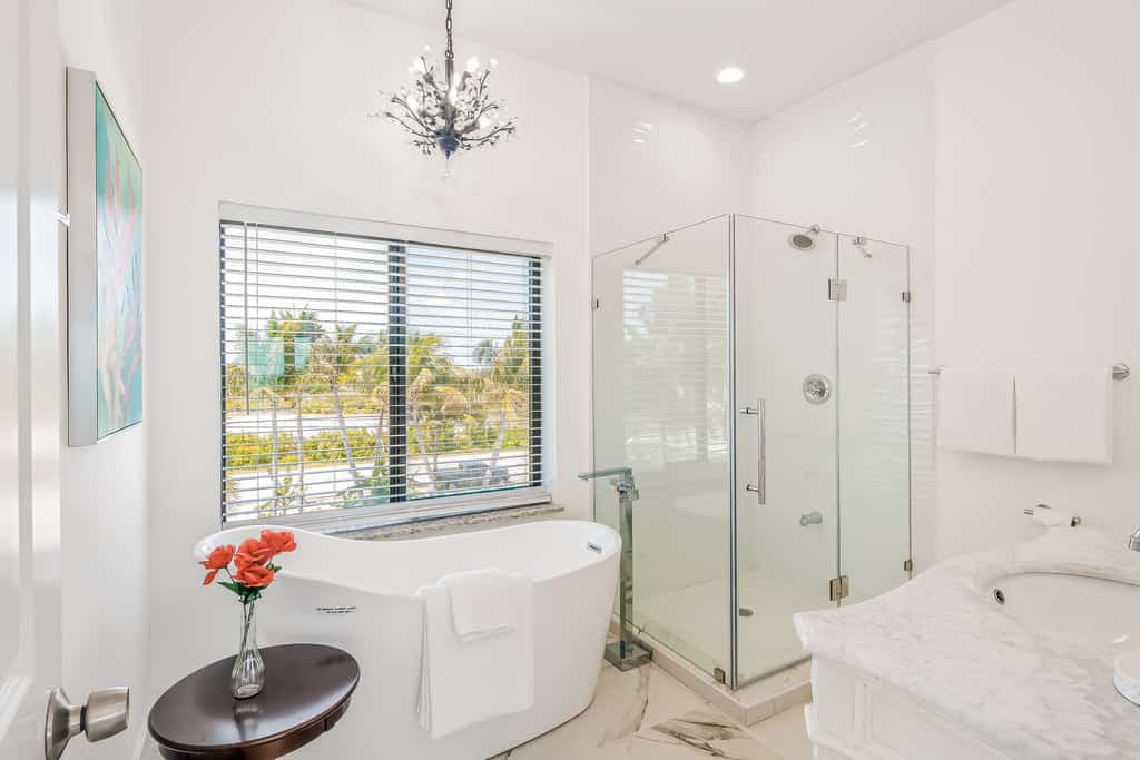 a vase of red flowers really pops in this sleek white bathroom