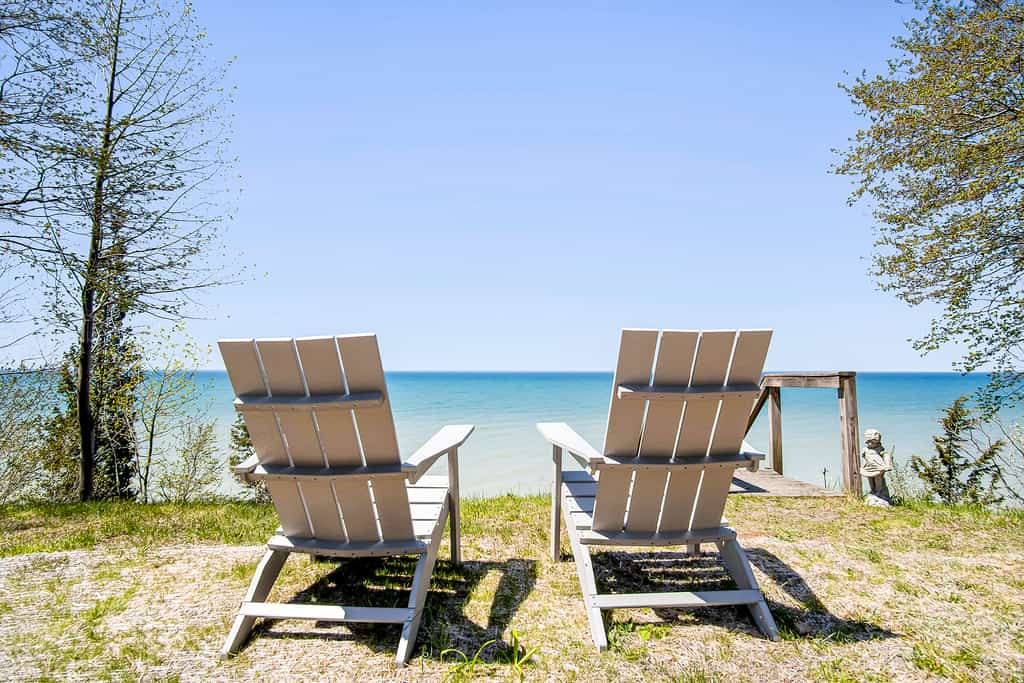 two white chairs by the edge of a lake