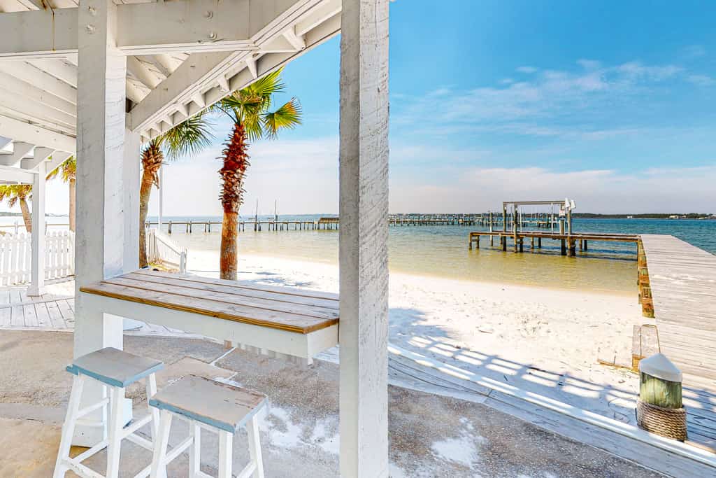 counter table with two chairs overlooks sandy beach and dock under navarre florida vacation home