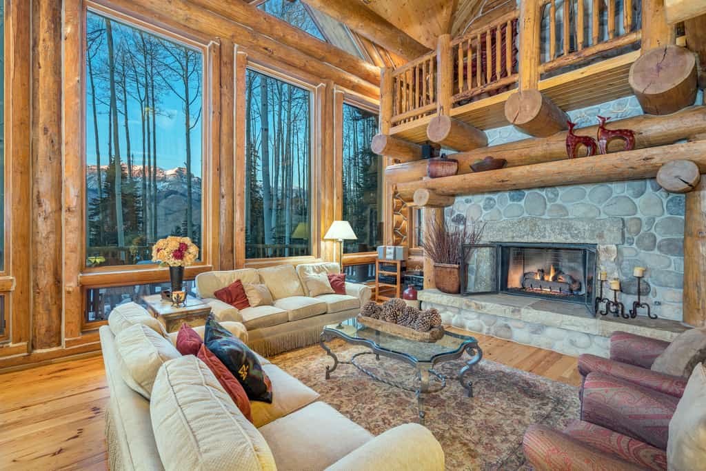 hearth of cabin in colorado with cozy couches and floor to ceiling windows