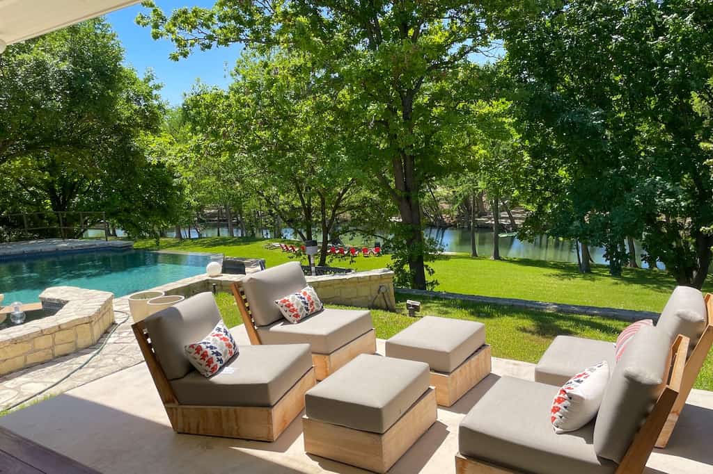 Deck chairs with tables and a pool in the background at a vacation rental in Hunt, TX.