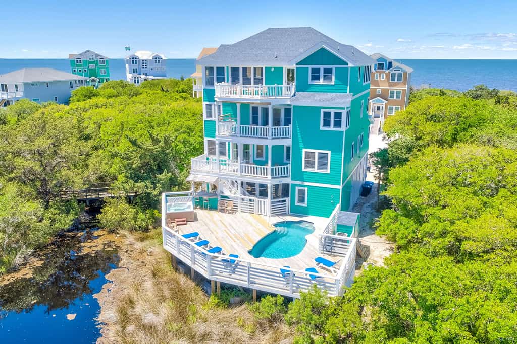 large turquoise home with a pool in the outer banks