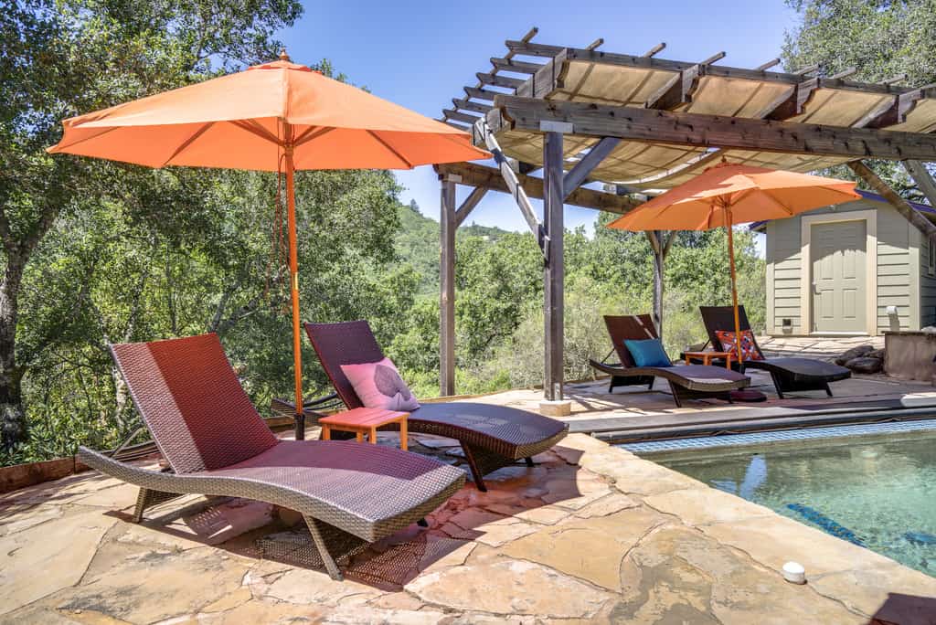 Lounge chairs with umbrellas for shade set up by a vacation rental pool