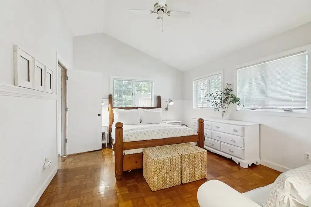 furnished bedroom with white walls and wood floors