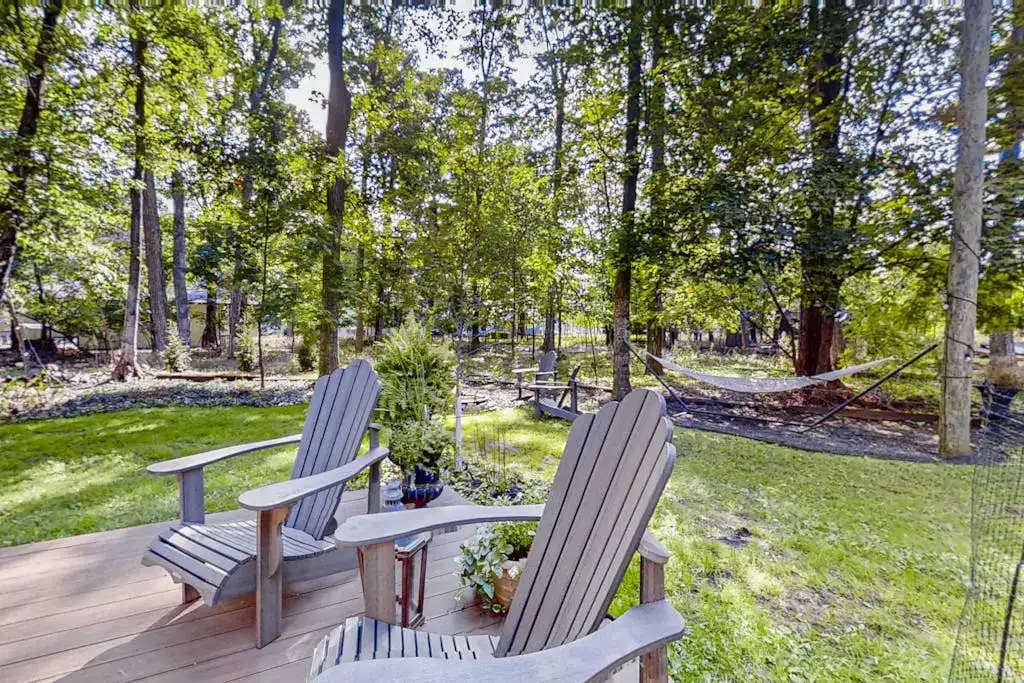 backyard with adirondack chairs on a deck and a hammock in the yard
