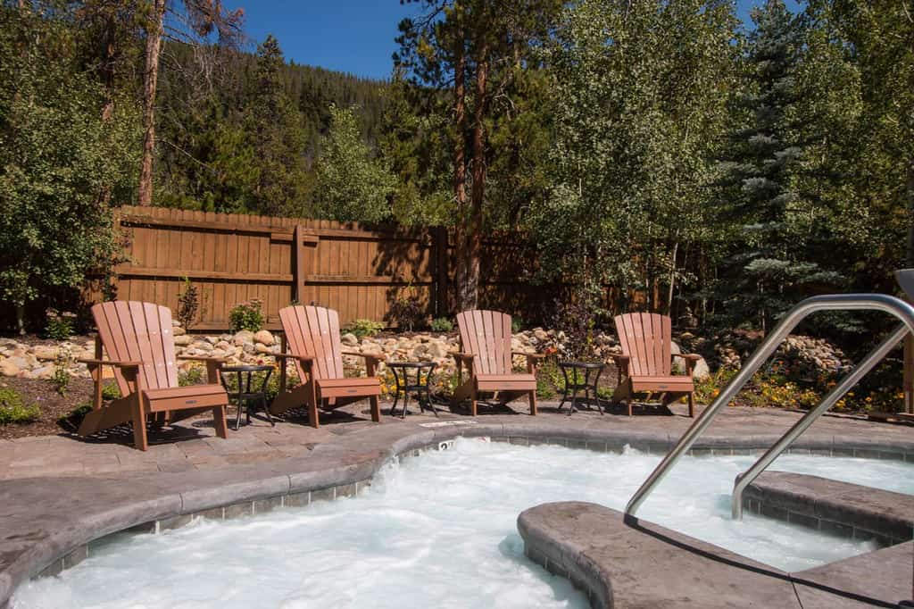outdoor hot tub surrounded by adirondack chairs