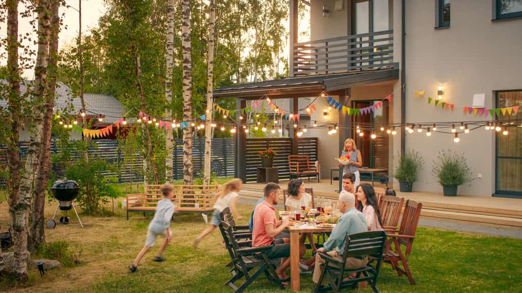 adults sit outside a vacation rental and enjoy a meal while children play